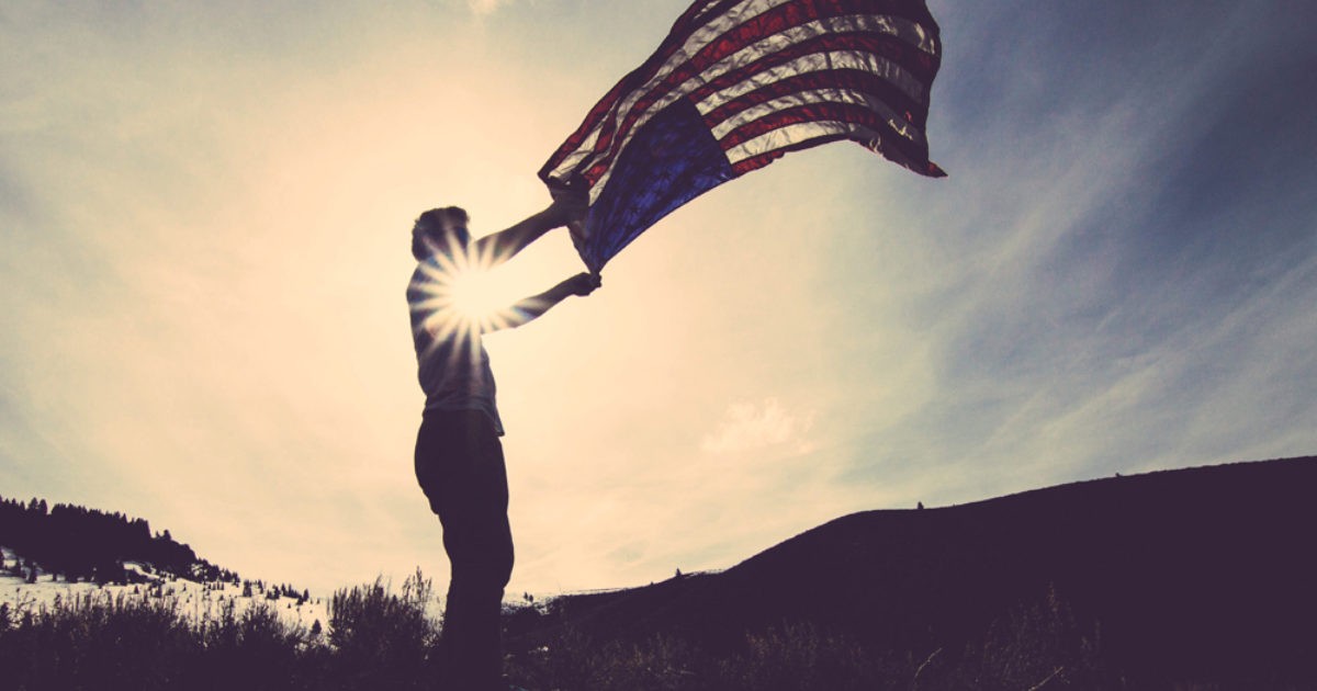 Person holding a flag during sunset