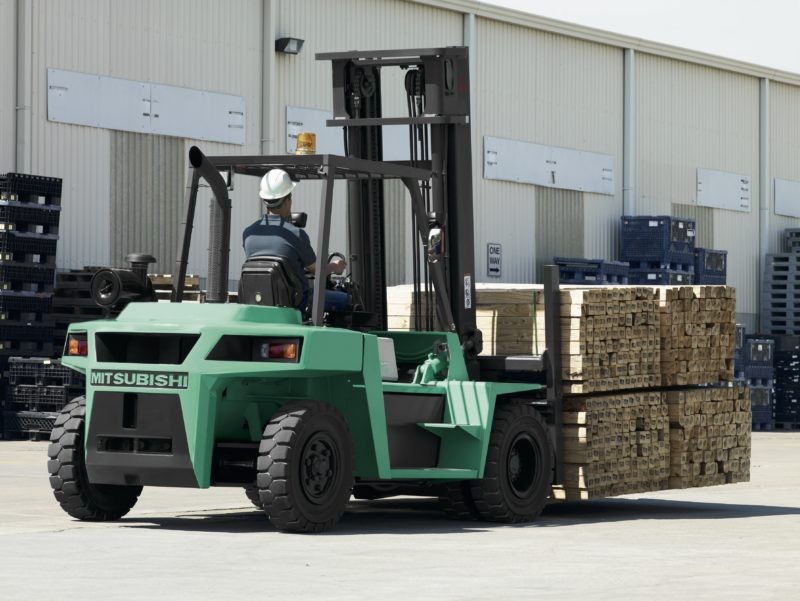 Mitsubishi pneumatic tire forklift outside carrying a load of lumber
