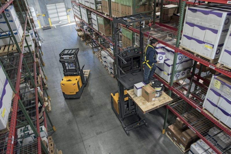 Two narrow aisle forklifts in warehouse aisle