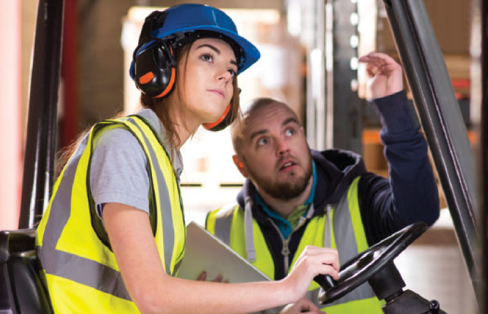 Man training a woman on a forklift